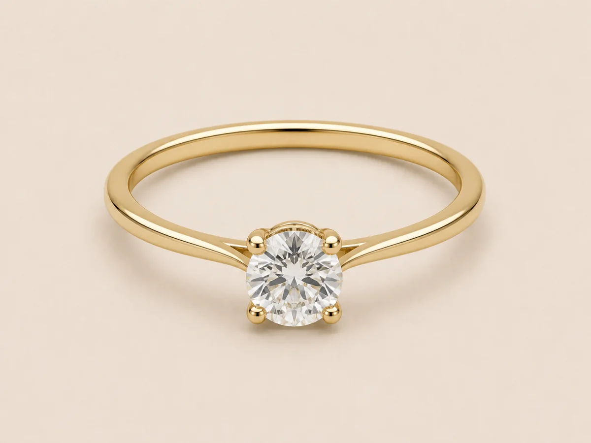 Yellow-gold round solitaire with a slim plain band and connected four-prong setting, shown in a three-quarter product view.