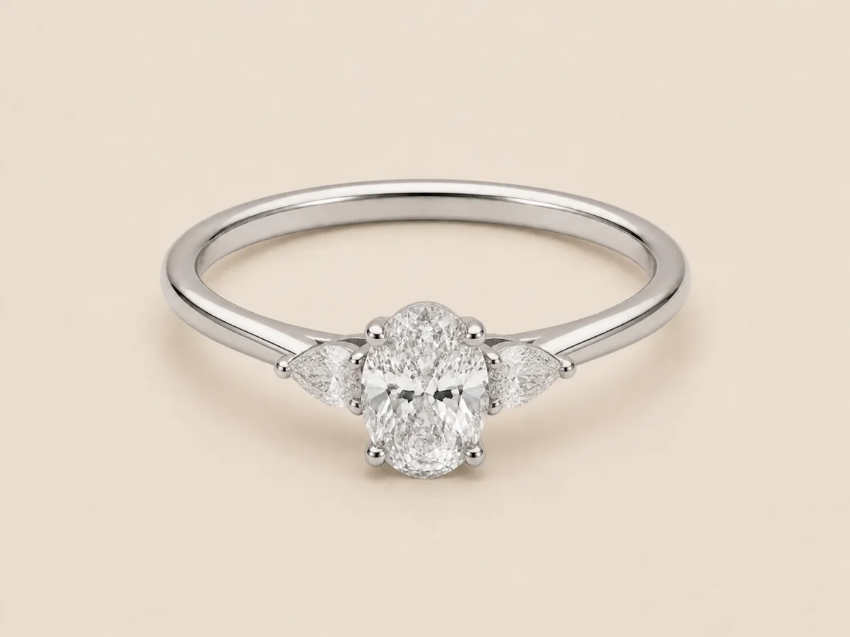 White-metal oval ring with two balanced pear-shaped side stones and a plain connected band, shown in a three-quarter product view.